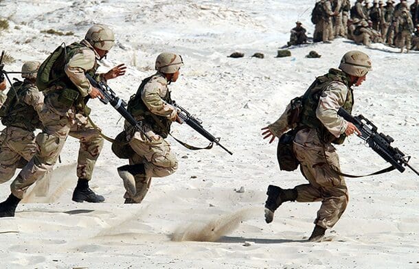 A group of soldiers running in the desert.