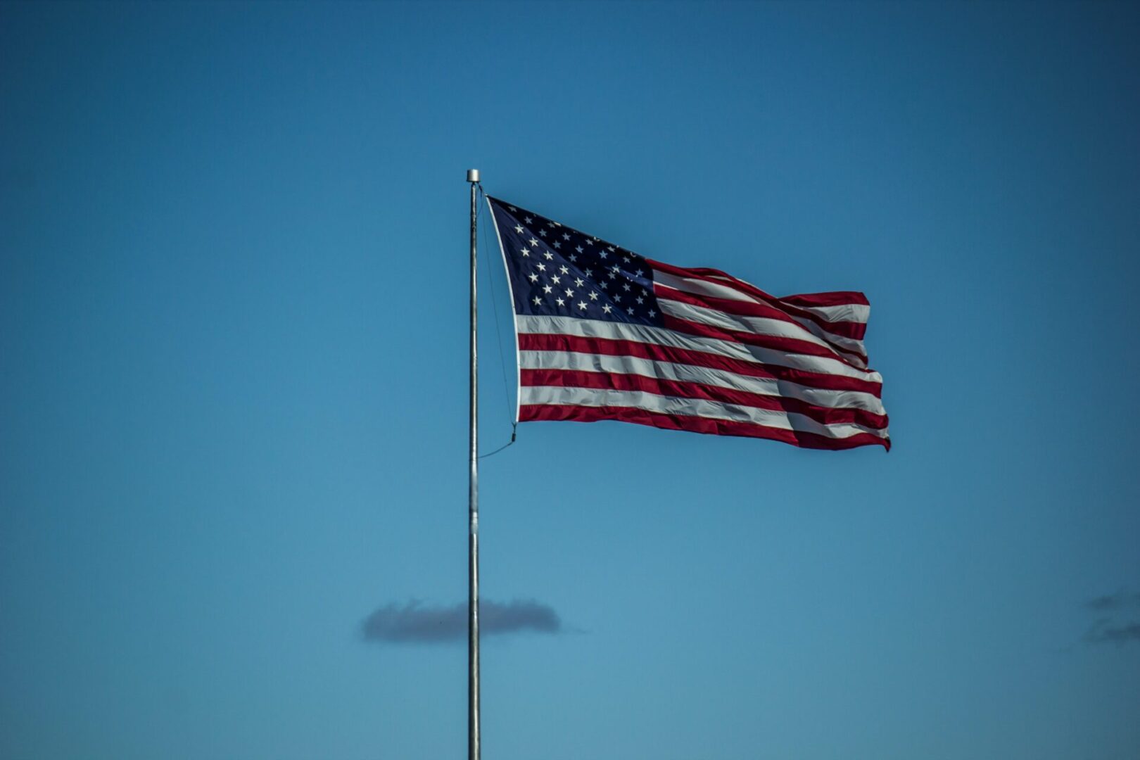 A flag flying in the wind on top of a pole.