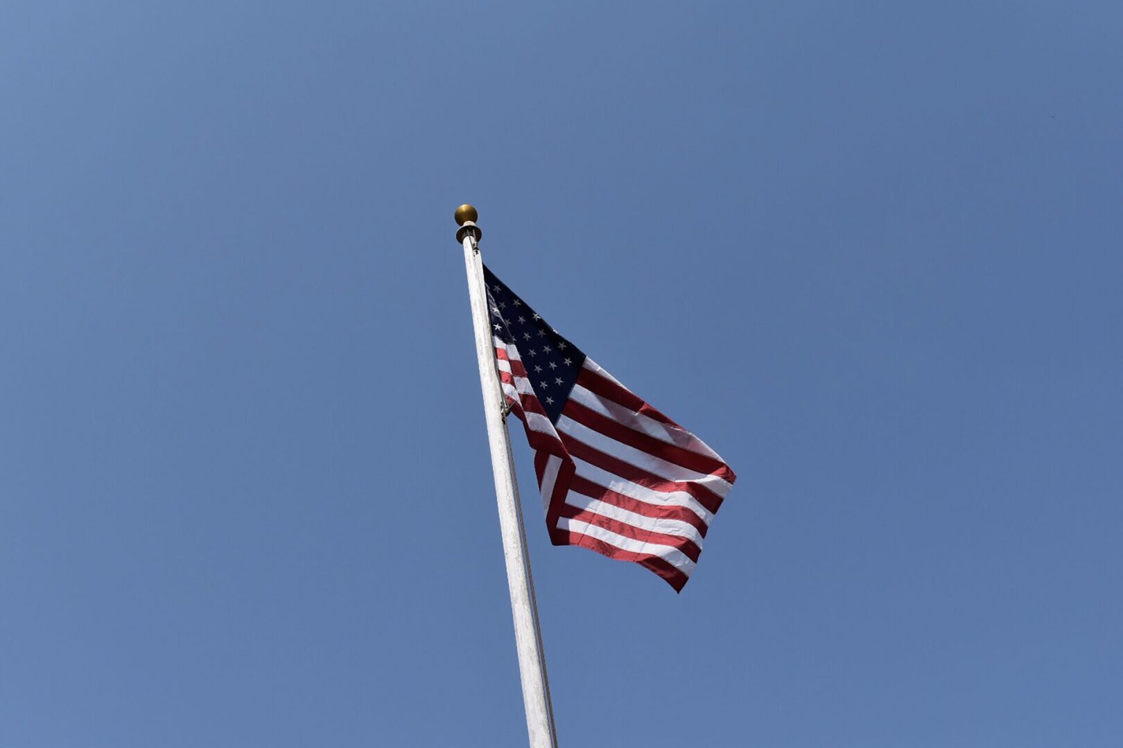 A flag flying in the wind on top of a pole.