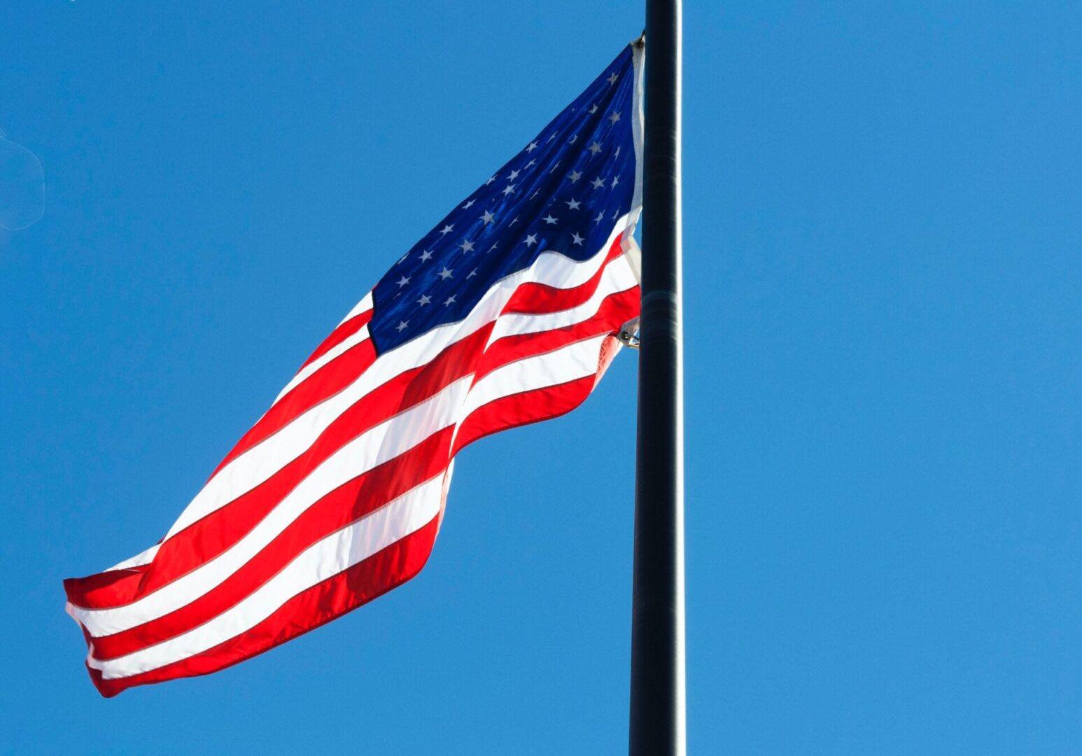 A flag flying at half-staff in front of the sky.