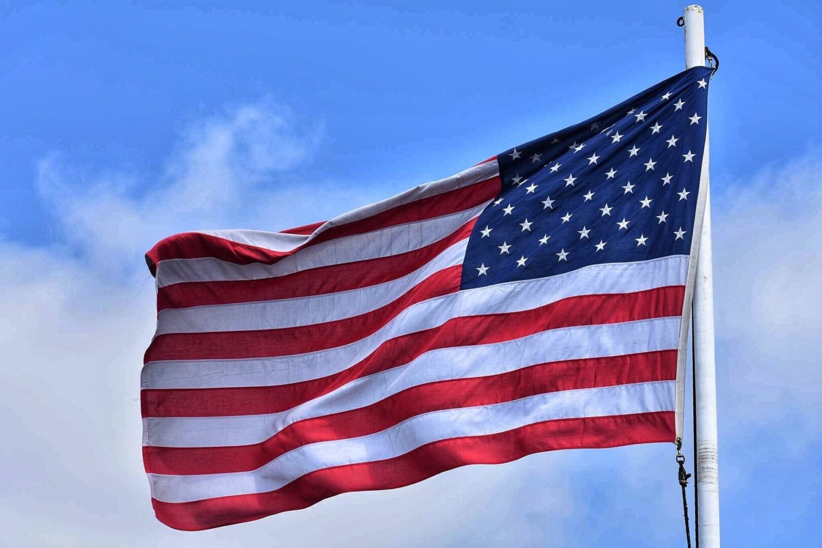 A flag flying in the wind on top of a pole.